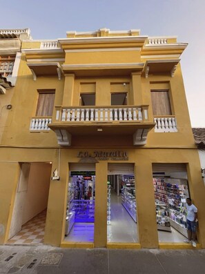 A two-story building with a commercial ground floor, a balcony, and a sign indicating a commercial center. - Hostal Casa Torres Centro Historico Adults Only (Cartagena)