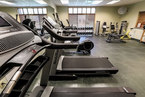Une salle de sport équipée de tapis de course, d’haltères et d’appareils d’exercice.