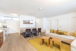 Ein modernes Wohnzimmer mit Essbereich, einer Sofagarnitur und einer Küche.