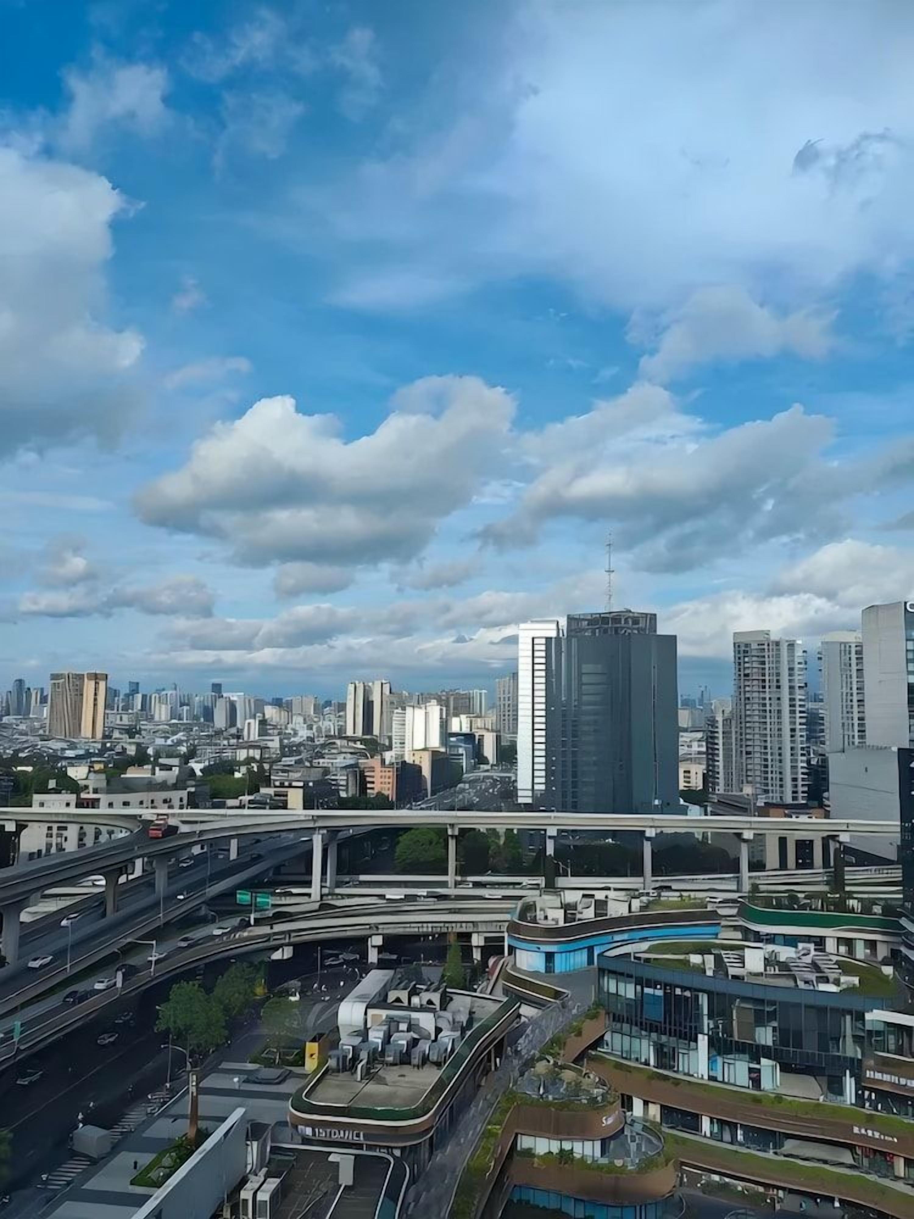 A cityscape with multiple high-rise buildings, a complex network of highways, and a clear sky.