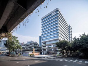 Un bâtiment moderne à la façade incurvée, doté de plusieurs étages et surplombant un ciel dégagé.