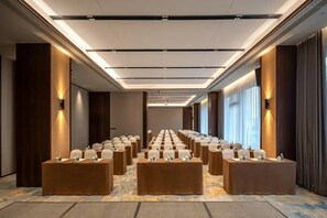 Une salle de conférence avec de longues tables, des chaises et un sol recouvert de moquette.