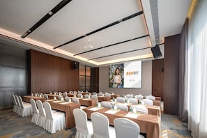 A conference room with long tables, chairs, and a projector screen.