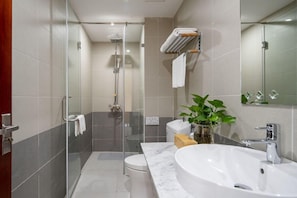 Un baño moderno con ducha envuelta en vidrio, un lavamanos blanco y un espejo.