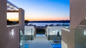 A modern rooftop pool area with glass railings and a view of the water. - Sun & Sea Plus Resort (Apokoronas)