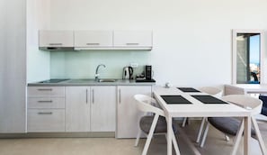 A modern kitchen with a dining area, including cabinets, a sink, a coffee maker, and a table with chairs.