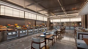Zona ristorazione di un hotel moderno con un lungo bancone, diverse opzioni di posti a sedere e vista sulla cucina sullo sfondo.