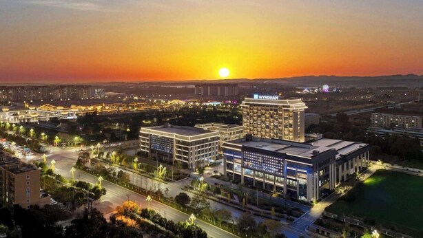 Paesaggio urbano al tramonto, con un hotel di grande rilievo al centro.