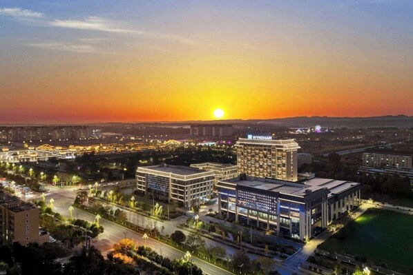 Bybillede i solnedgang med en markant hotelbygning i centrum.