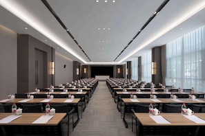 A conference room with rows of tables, chairs, and water bottles, featuring a modern design with a neutral color palette. - Wyndham Qujing Luliang (Qujing)