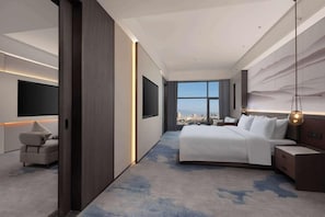 A modern hotel room with a large bed, a sofa, a TV, and a city view. - Wyndham Qujing Luliang (Qujing)