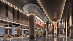 Un'ampia hall con soffitto alto, pavimenti in marmo lucido e lampade moderne.