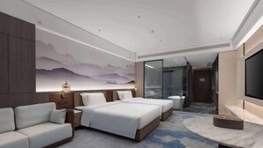 Camera d'albergo con un letto, una poltrona, una TV e un murale raffigurante un paesaggio montano.