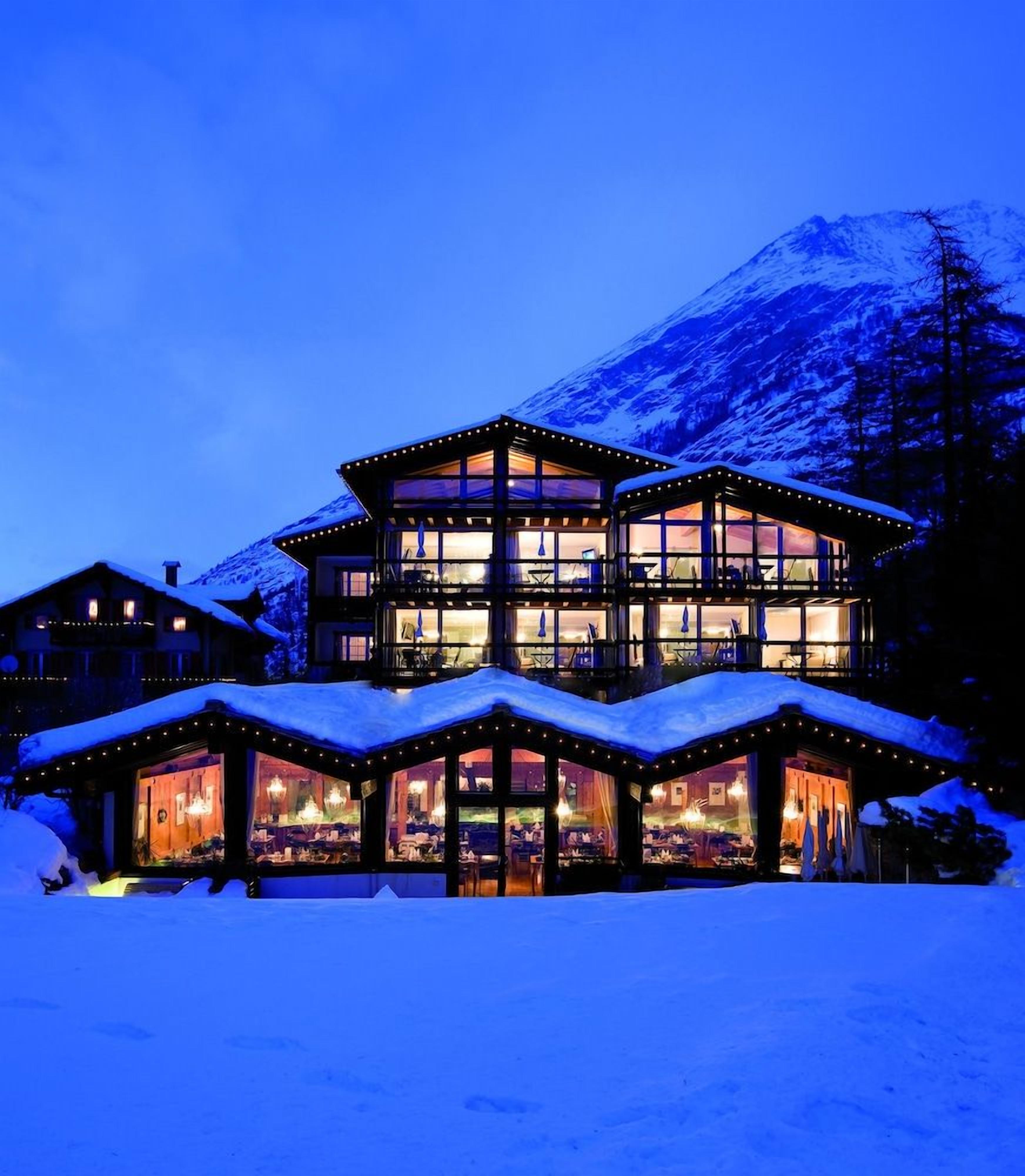 A multi-story building with large windows and a balcony, surrounded by snow.