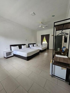 A hotel room with three beds, a bathroom, and a large mirror.