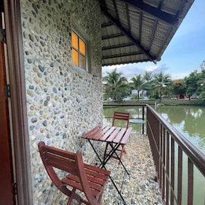 A stone building with a balcony, a wooden table, and two chairs.