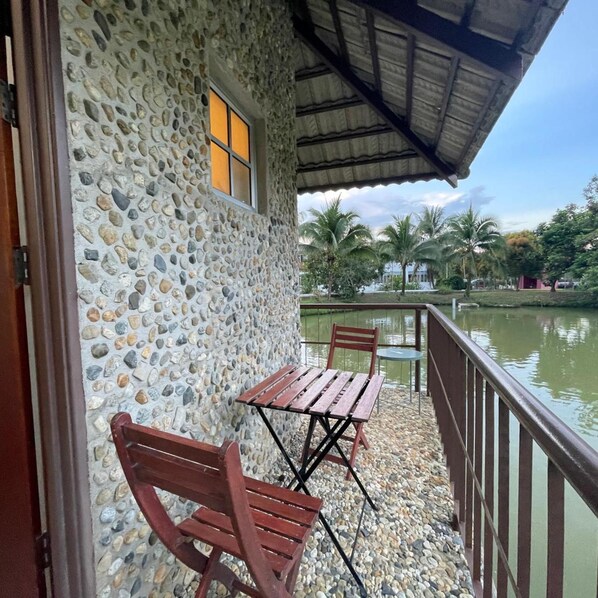 A stone building with a balcony, a wooden table, and two chairs.