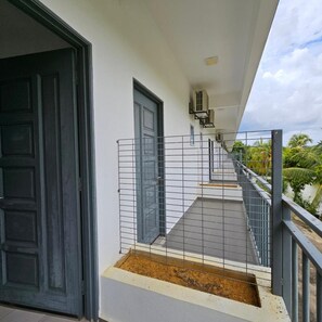 A balcony with a metal railing, a door, and a small planter box with soil.