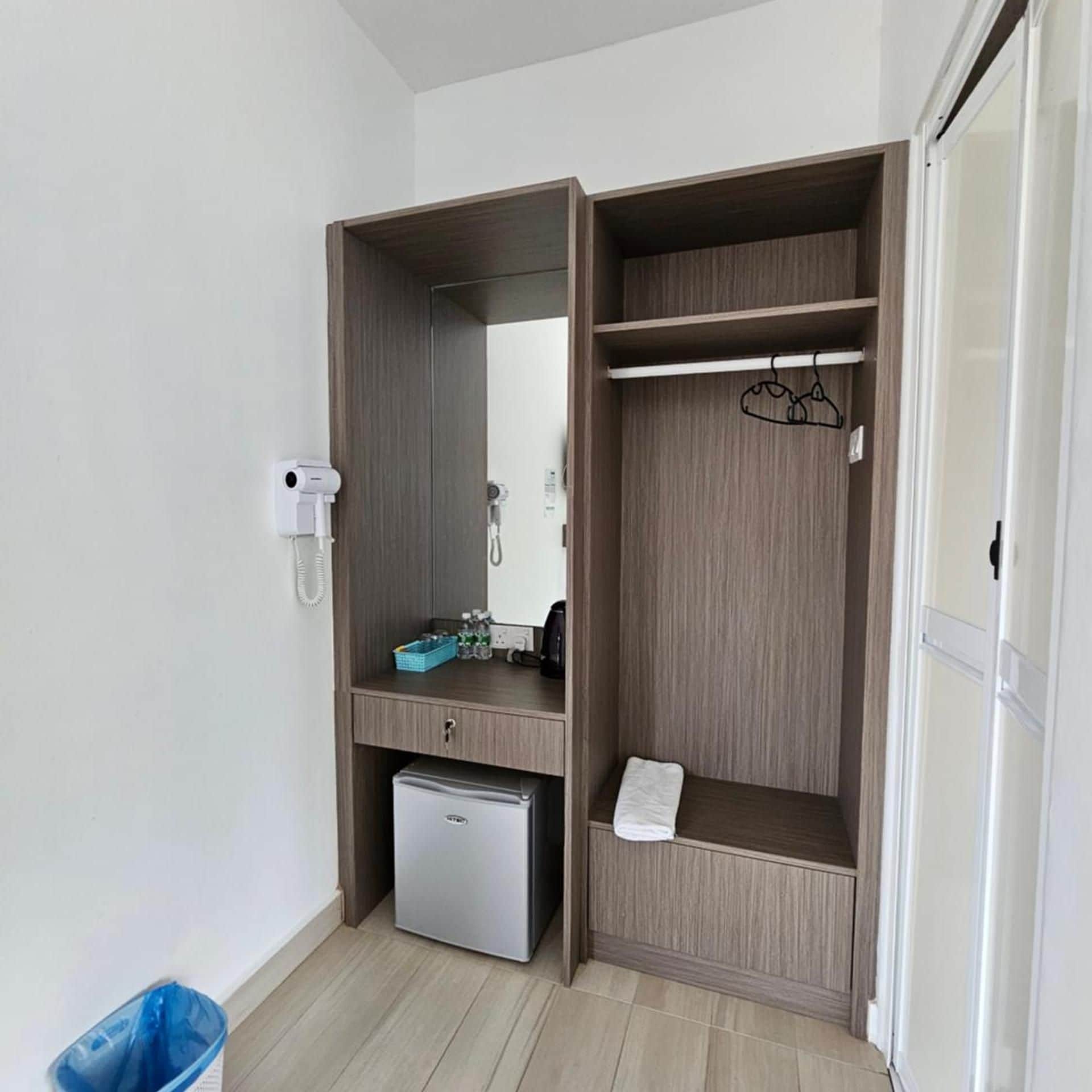 Habitació compacta amb armari de paret, nevera petita, mirall i paraigua.