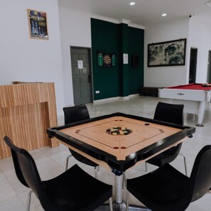 A room with a foosball table, a pool table, and a dartboard.