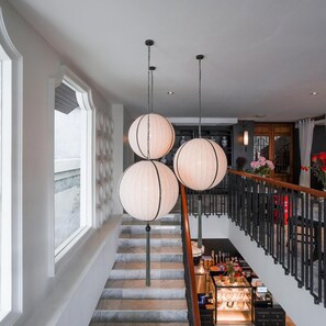 Un escalier avec une rampe, un lustre et une vue sur une pièce contenant une table et des chaises.