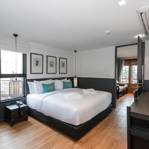 Une chambre d’hôtel moderne avec un grand lit, une table de chevet, une lampe et des œuvres d’art encadrées accrochées au mur.