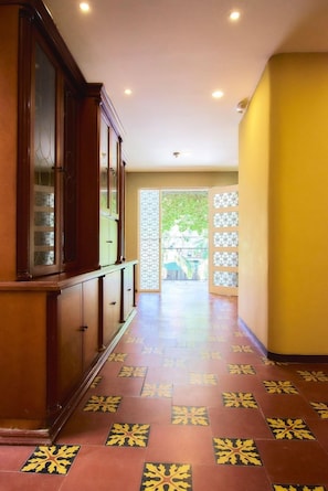 A hallway with patterned flooring leading to a door with a glass panel. - Brana Hotel (Medellín)