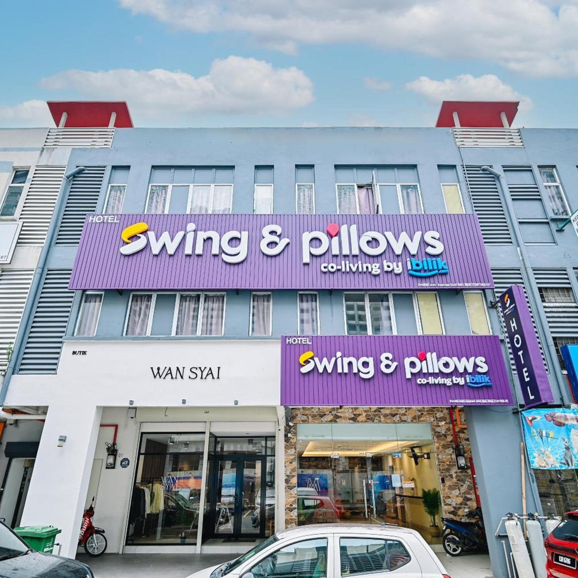Un hotel con un letrero morado que dice 'Swing & Pillows' y un letrero 'Wan Syi' debajo.