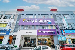A hotel named 'Swing & Pillows' with a purple sign, located on a street with other businesses. - Swing & Pillows Myhome Wangsa Maju (Kuala Lumpur)