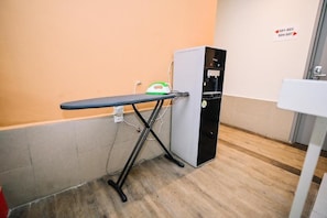 A room with a wooden floor, a black ironing board, a green and white iron, and a water dispenser. - Swing & Pillows Myhome Wangsa Maju (Kuala Lumpur)