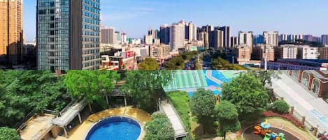 A high-rise building with a swimming pool and playground in the foreground.