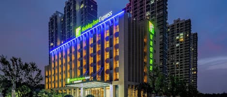 A multi-story hotel with a prominent 'Holiday Inn Express' sign, a covered entrance, and surrounding greenery.