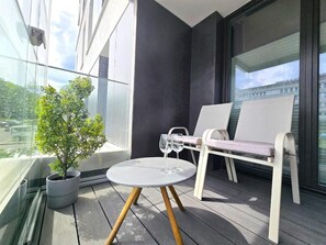 Ein Balkon mit einem Blumentopf, einem runden Tisch und zwei Stühlen.