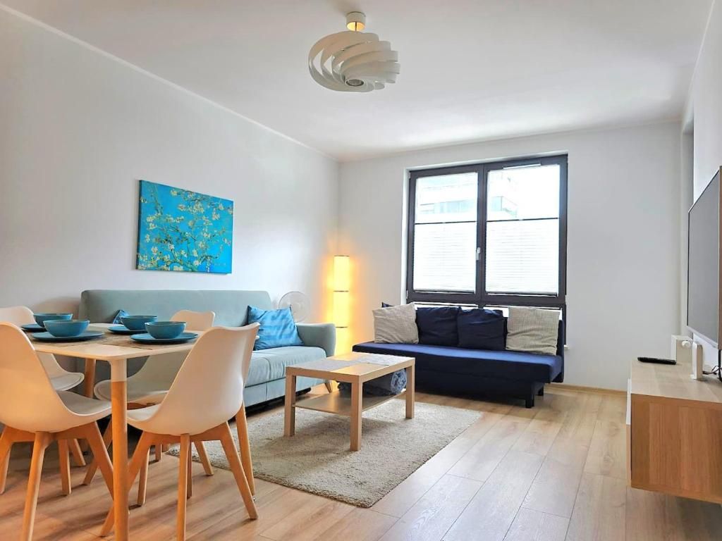 A modern living room with a dining area, a sofa, a TV, and a painting on the wall.