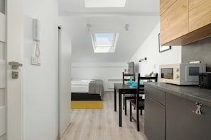 A compact kitchen with a microwave, a dining table with chairs, and a small window above the sink. - Cracow | 11 Mazowiecka Street | Cosy Studio | Air conditioning (Kraków)
