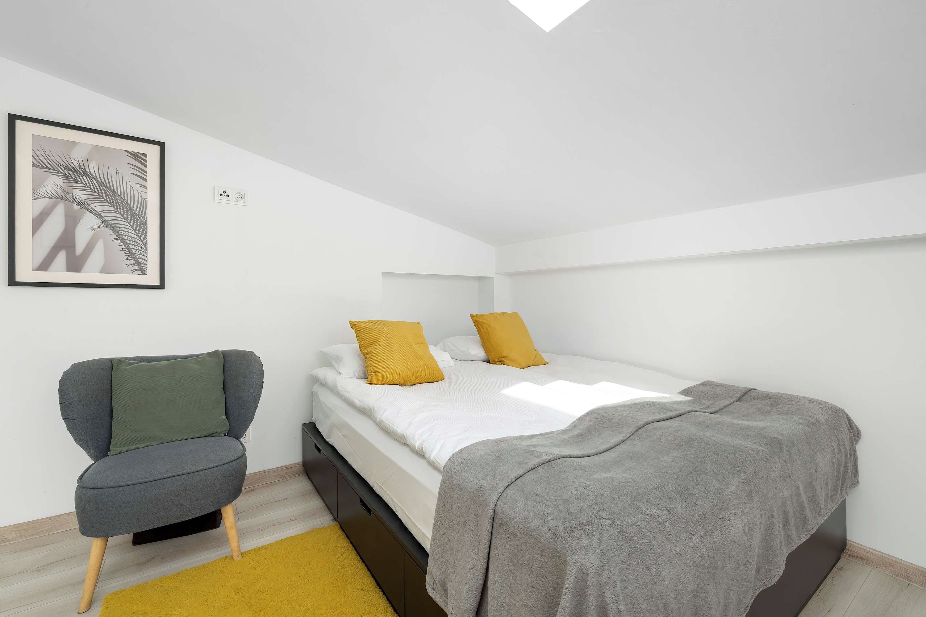 Une chambre à coucher moderne avec un lit, une chaise et un tableau encadré accroché au mur.