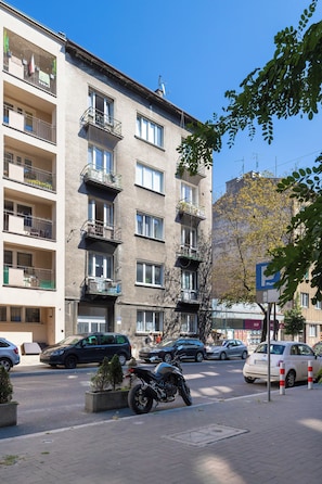 A multi-story building with balconies, parked cars, and a motorcycle on the street. - Cracow | 11 Mazowiecka Street | Cosy Studio | Air conditioning (Kraków)