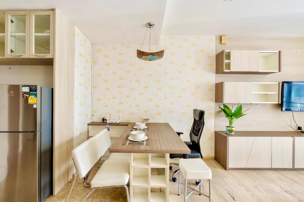 A modern kitchen with a wooden table, white chairs, a built-in oven, and a television on the wall.