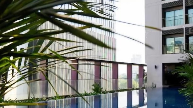A modern building with a rooftop pool, surrounded by greenery and a clear view of a tall building in the background. - Noble Remix Bangkok (Krung Thep Maha Nakhon)