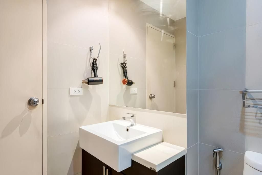 A modern bathroom with a white sink, a mirror, and a shower area.