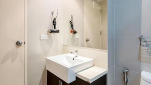 A modern bathroom with a white sink, a mirror, and a shower area. - Noble Remix Bangkok (Krung Thep Maha Nakhon)