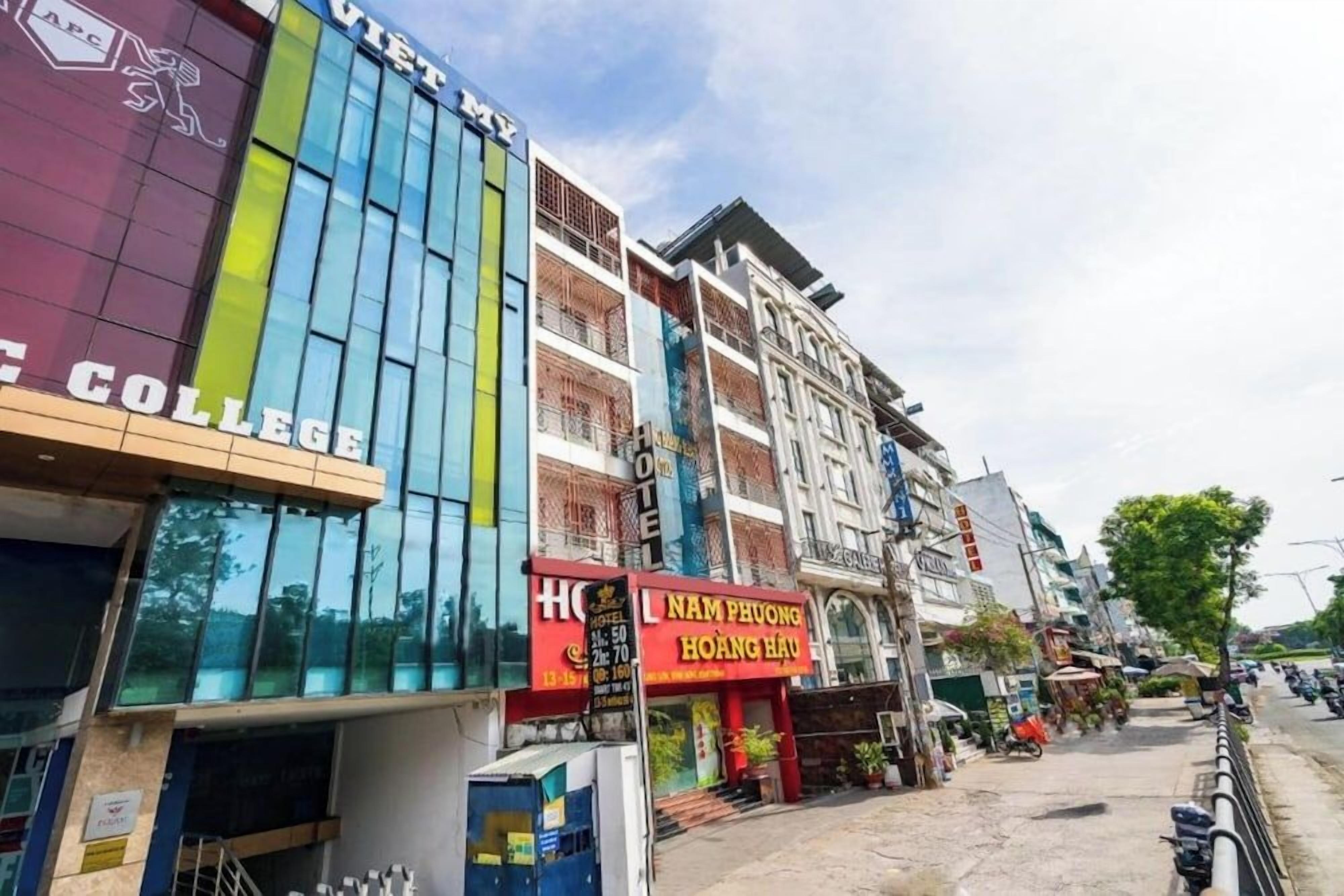 Un edificio de varios pisos con fachada moderna, un letrero de hotel y un restaurante llamado 'NAM PHUONG HOANG HAU' en la planta baja.