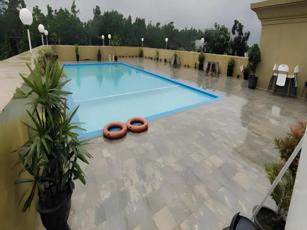 A rooftop pool area with a blue pool, potted plants, and outdoor seating.