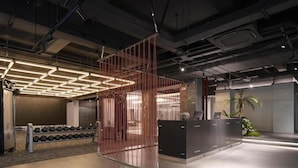 An indoor space with a reception desk, a wall-mounted dumbbell rack, and a partition with vertical lines. - Shenzhen Innogym Hotel (Shenzhen)