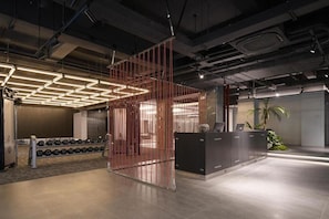 An indoor space with a reception desk, a wall-mounted dumbbell rack, and a partition with vertical lines. - Shenzhen Innogym Hotel (Shenzhen)
