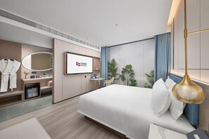 Une chambre d’hôtel moderne équipée d’un lit, d’une télévision, d’un bureau, d’un miroir et d’un mini-bar.