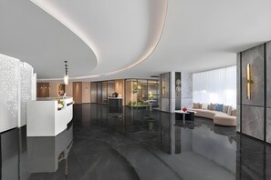 Un hall d’hôtel moderne avec un comptoir d’accueil, un espace salon et une grande fenêtre.