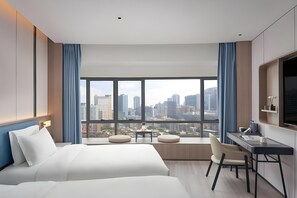 Une chambre d’hôtel avec un grand lit, un bureau, une chaise et une vue sur le paysage urbain.