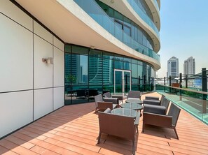 Eine Dachterrasse mit Außenmöbeln und einer Glaswand mit Blick auf eine Stadtlandschaft.