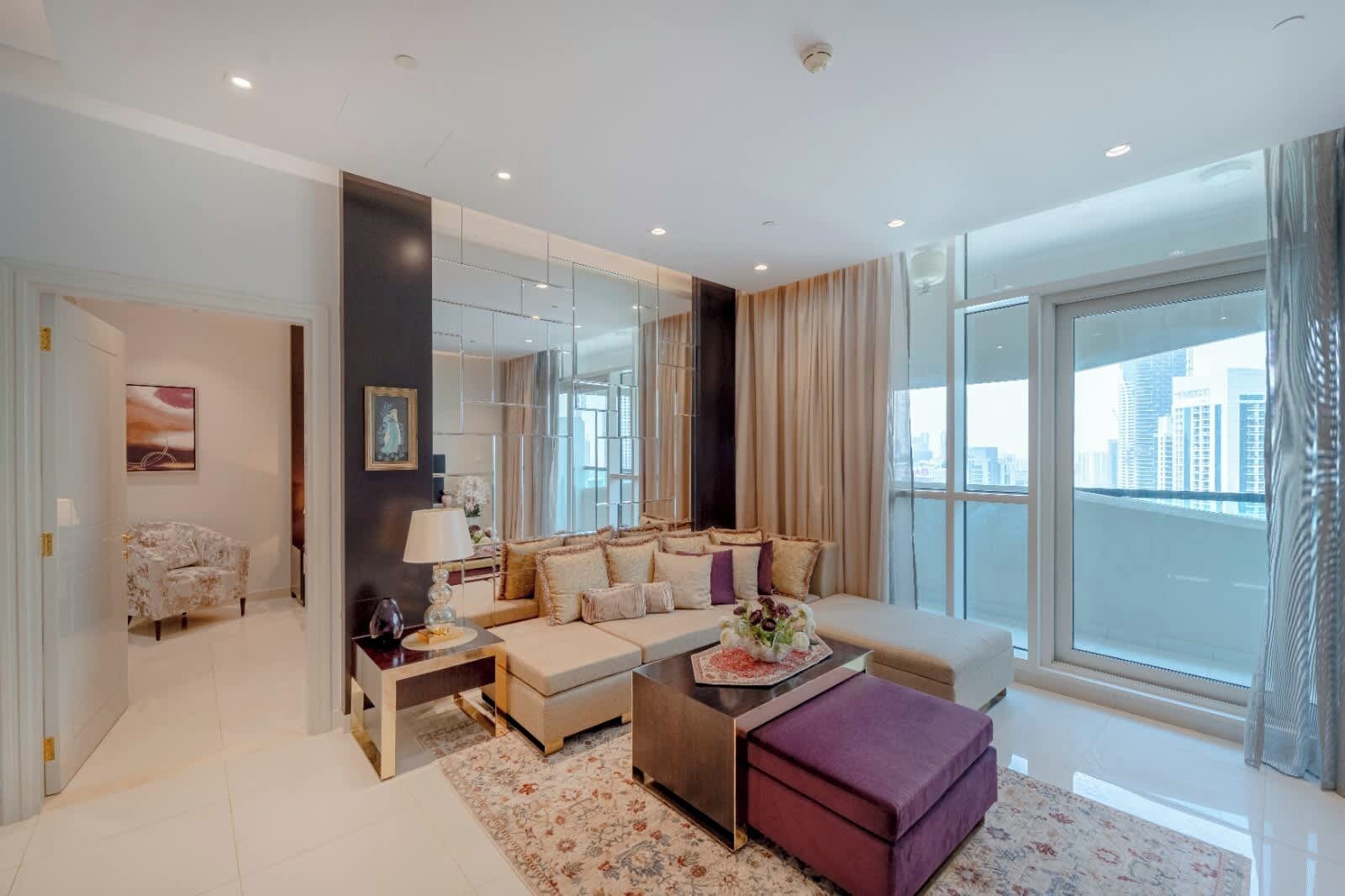 A modern living room with a sofa, coffee table, and a view of the city through large windows.